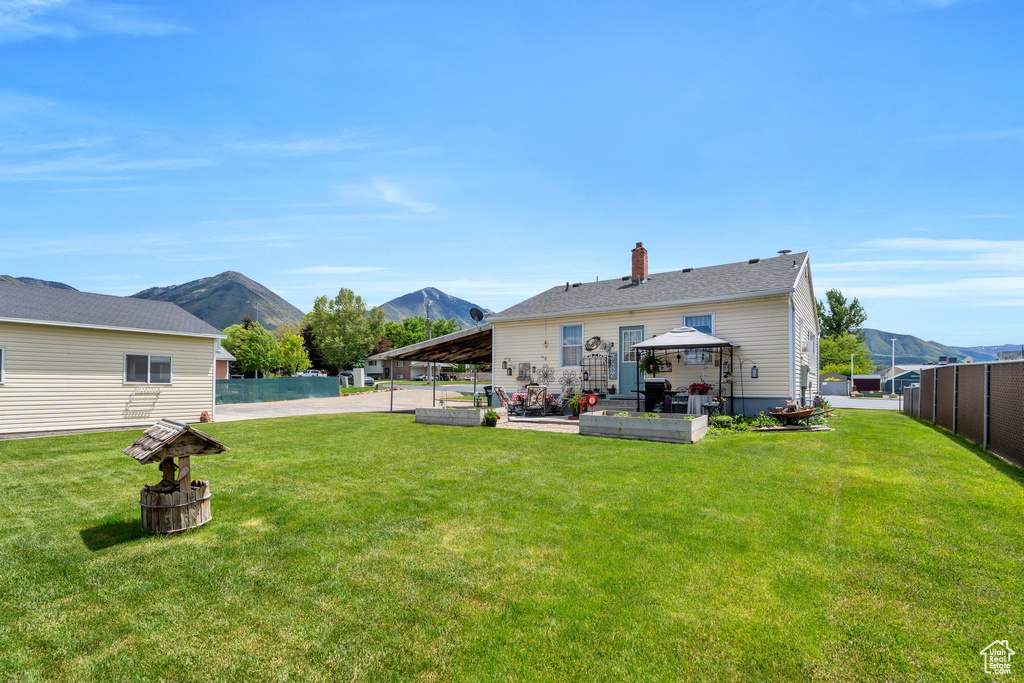 Rear view of house featuring a mountain view, a gazebo, a patio area, and a chimney
