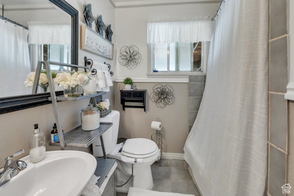 Full bathroom featuring a sink, tile patterned flooring, baseboards, toilet, and curtained shower