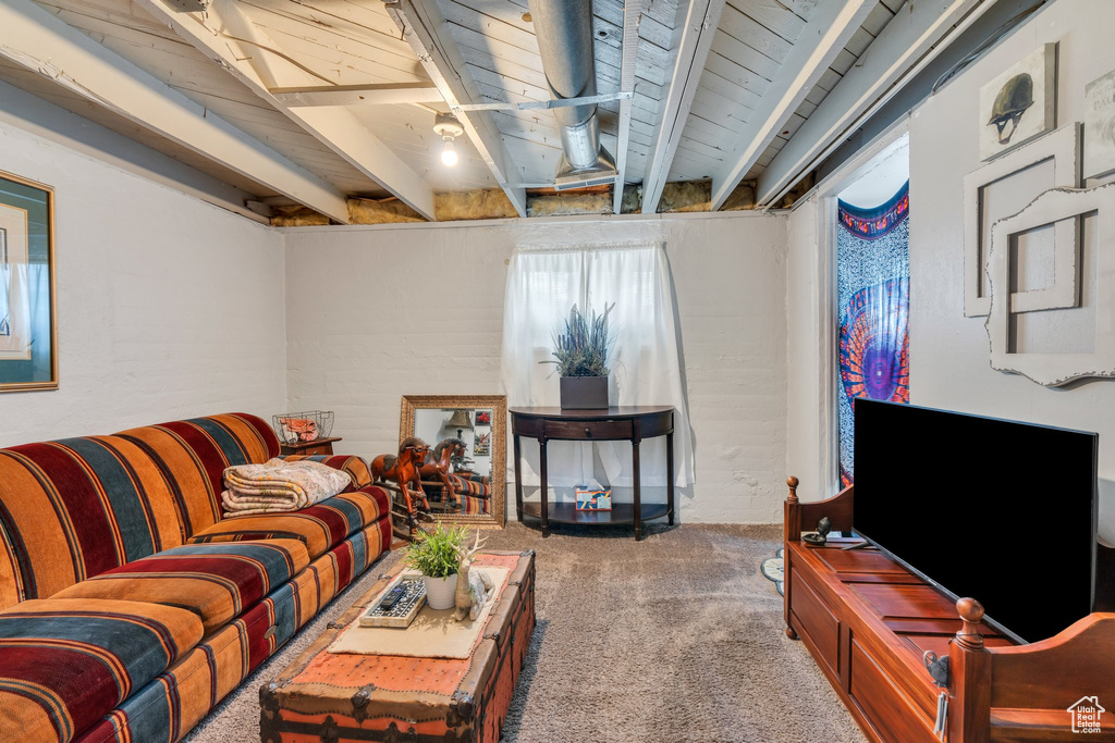 Living area with carpet and wooden ceiling with exposed beams