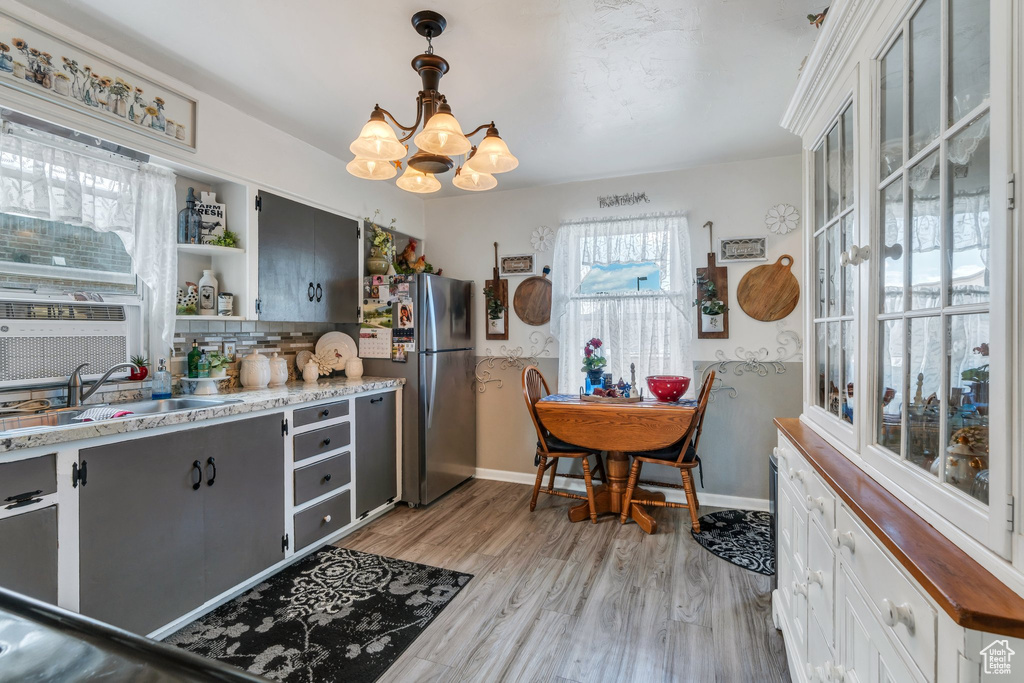 Kitchen with a chandelier, open shelves, freestanding refrigerator, a sink, and light wood finished floors