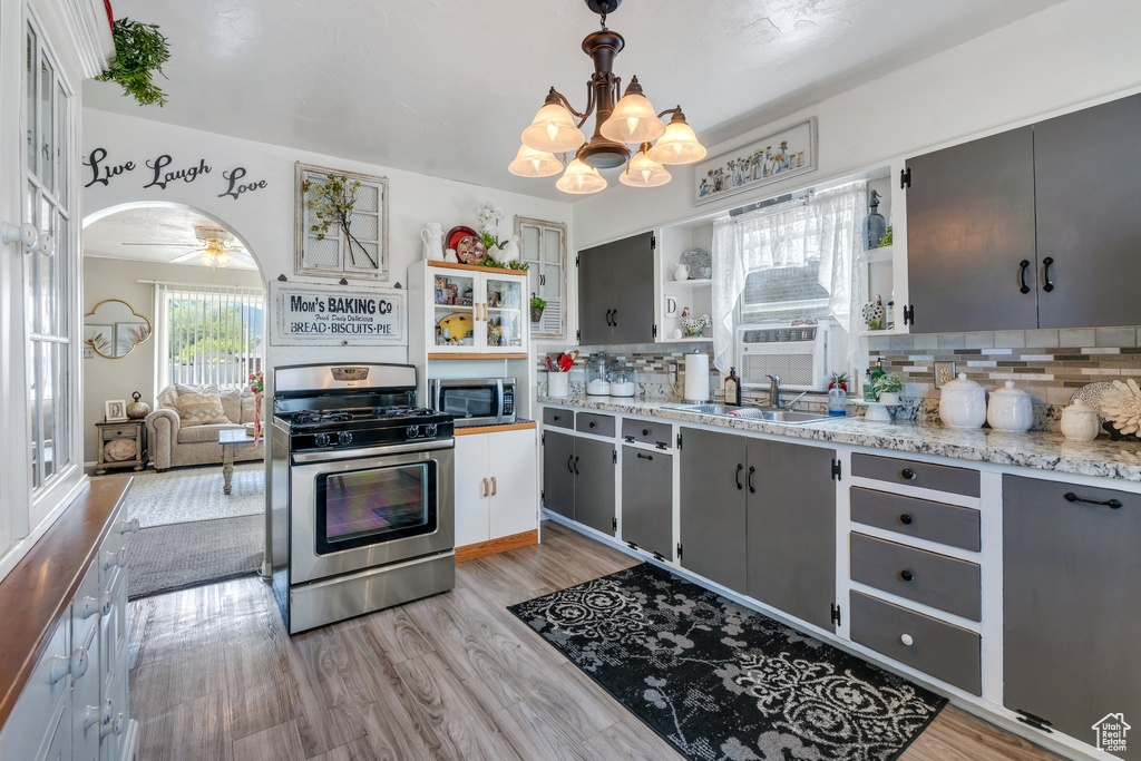 Kitchen featuring appliances with stainless steel finishes, a chandelier, open shelves, gray cabinetry, and decorative backsplash