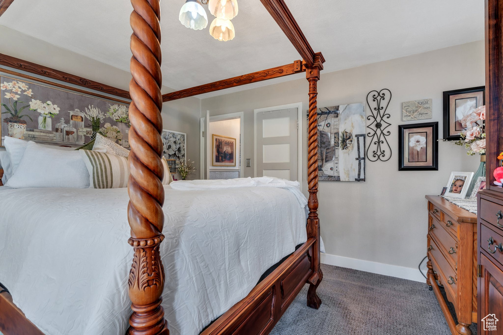 Bedroom featuring dark colored carpet, baseboards, and a chandelier