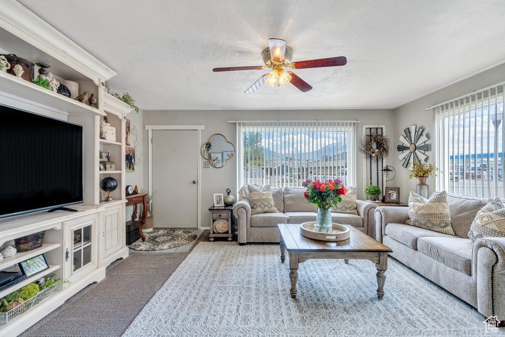 Living area featuring plenty of natural light, ceiling fan, a textured ceiling, and carpet floors