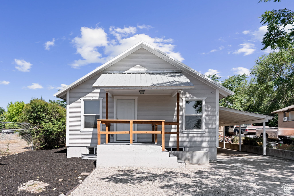 View of front of house with an attached carport, metal roof, and a porch