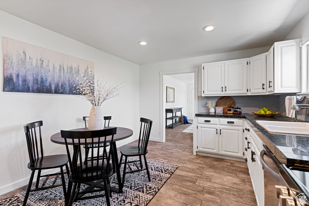 Kitchen featuring a sink, white cabinetry, recessed lighting, light wood-style floors, and baseboards
