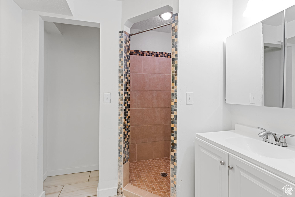 Bathroom with a shower stall, vanity, baseboards, and tile patterned floors