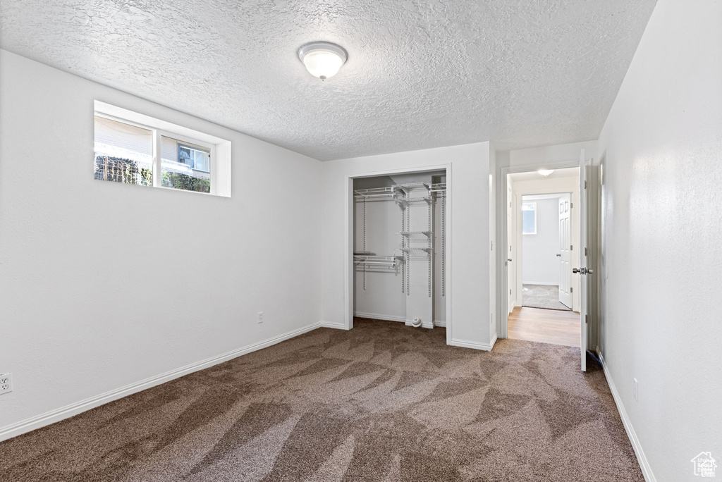 Unfurnished bedroom with carpet flooring, a textured ceiling, a closet, and baseboards