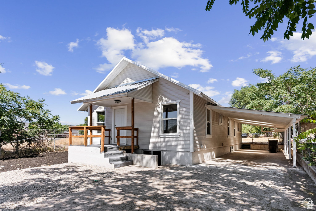 View of front of house with an attached carport, driveway, and metal roof