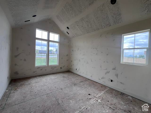 Empty room featuring vaulted ceiling and baseboards