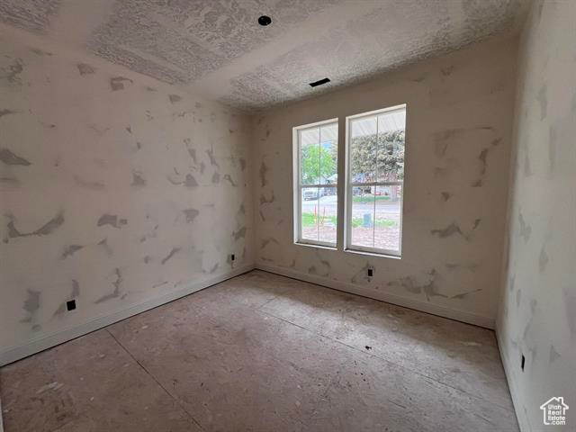 Empty room with baseboards and a textured ceiling