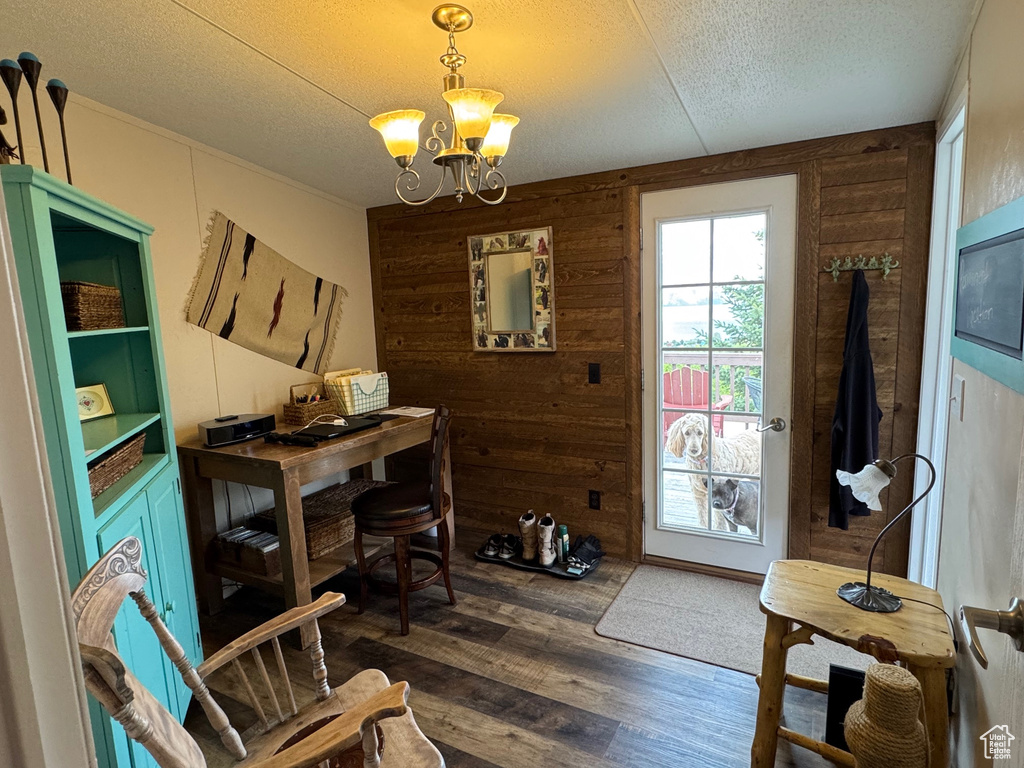 Home office with a chandelier, dark wood-type flooring, wood walls, and a textured ceiling