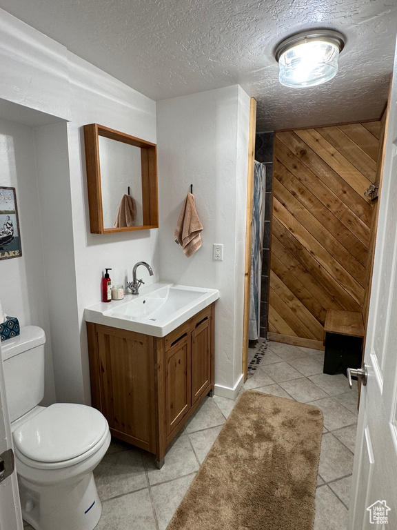 Bathroom with toilet, tile patterned flooring, vanity, curtained shower, and a textured ceiling