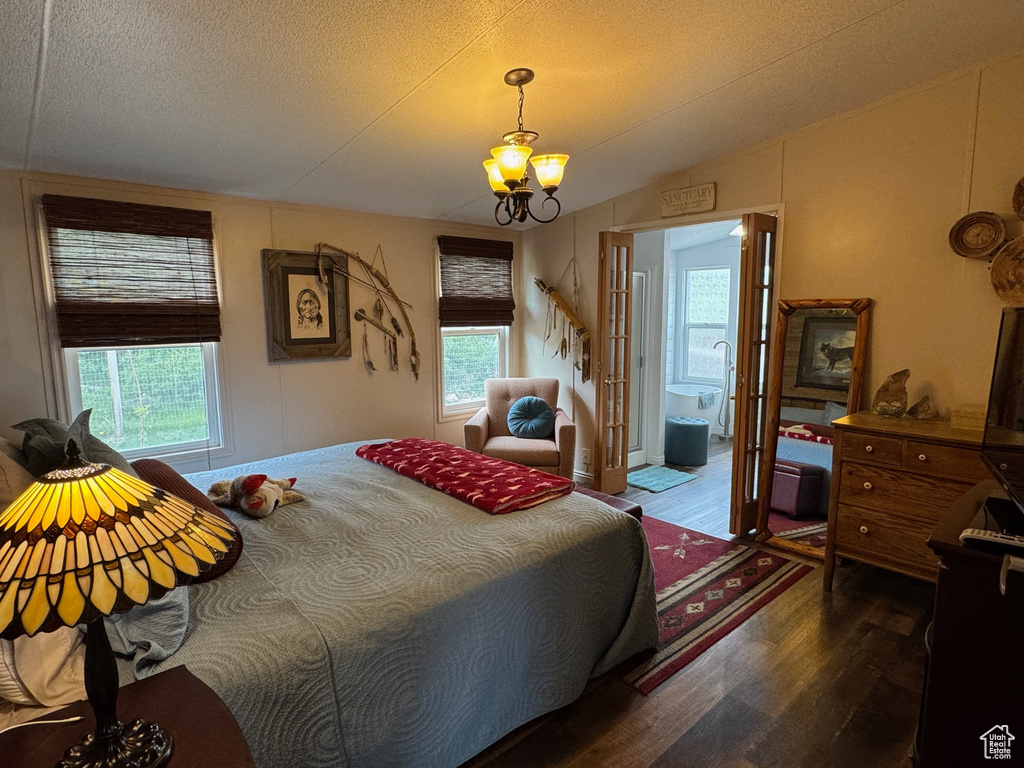 Bedroom featuring wood finished floors, lofted ceiling, a chandelier, and a textured ceiling