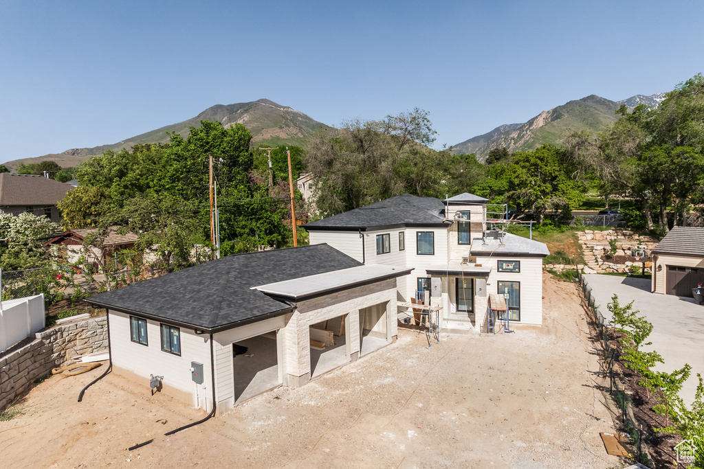 Back of house with a mountain view, a garage, and a shingled roof