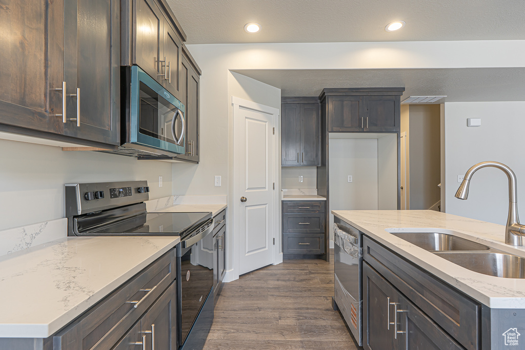 Kitchen featuring stainless steel appliances, a sink, dark wood-type flooring, recessed lighting, and light stone countertops