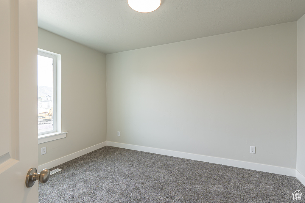 Unfurnished room featuring dark carpet and baseboards
