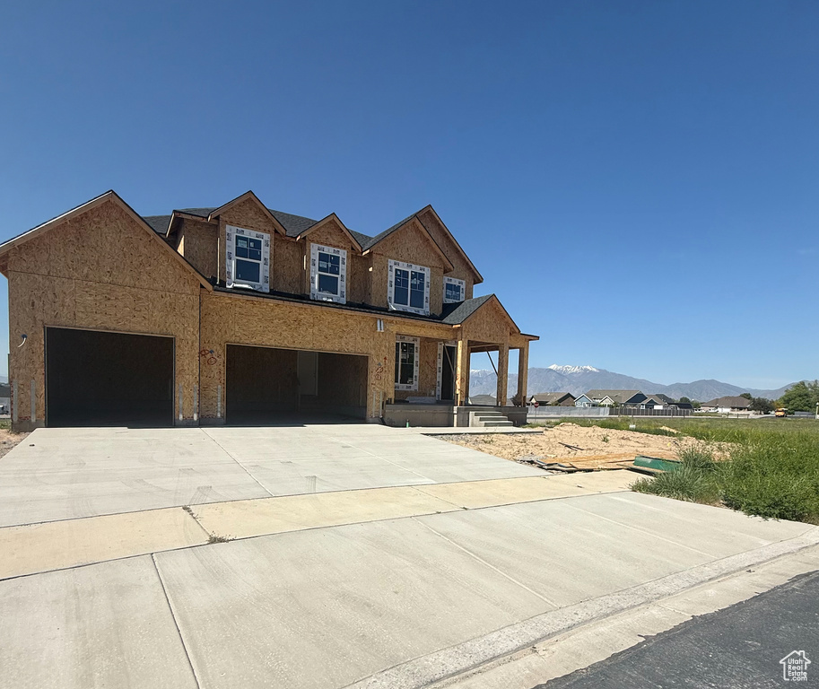View of front of house featuring driveway, a mountain view, stucco siding, covered porch, and a garage