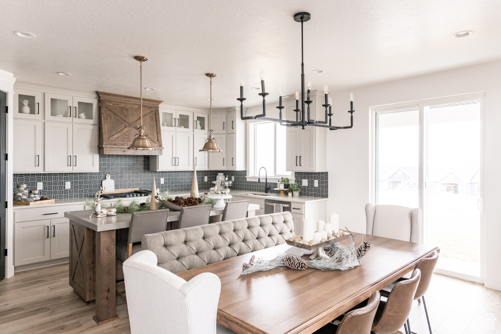 Dining space with light wood finished floors, a chandelier, and recessed lighting