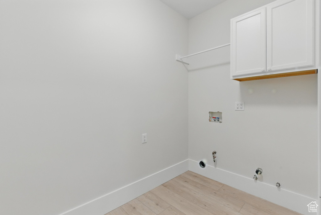 Clothes washing area featuring cabinet space, light wood-type flooring, hookup for a gas dryer, washer hookup, and baseboards