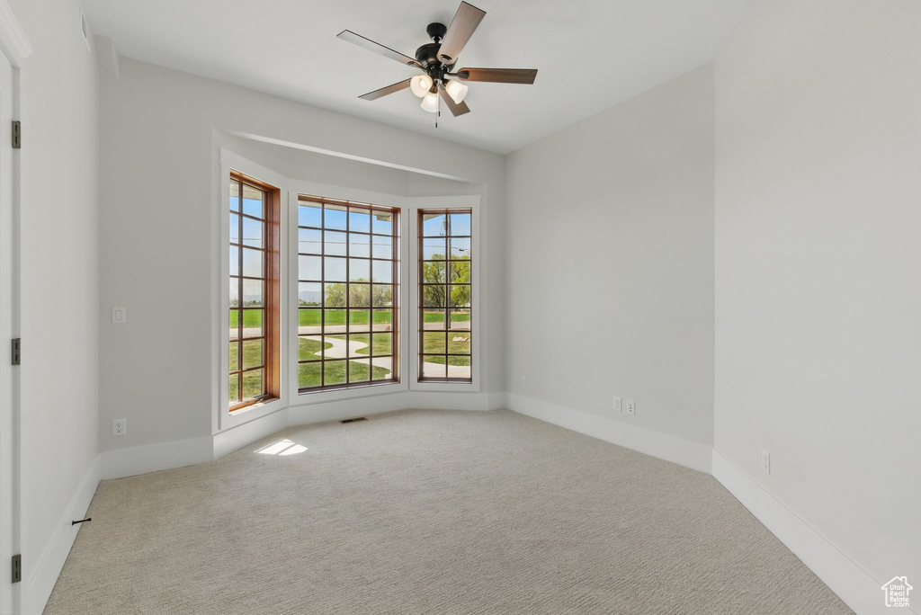 Empty room with visible vents, baseboards, ceiling fan, and carpet floors