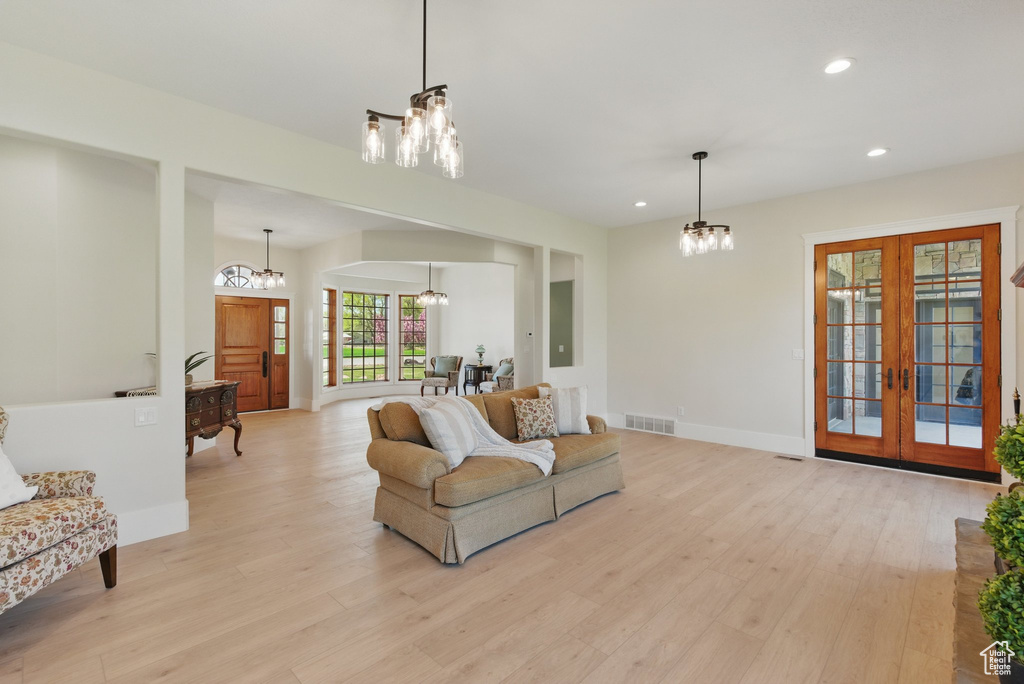 Living area with french doors, light wood-style flooring, a notable chandelier, visible vents, and recessed lighting