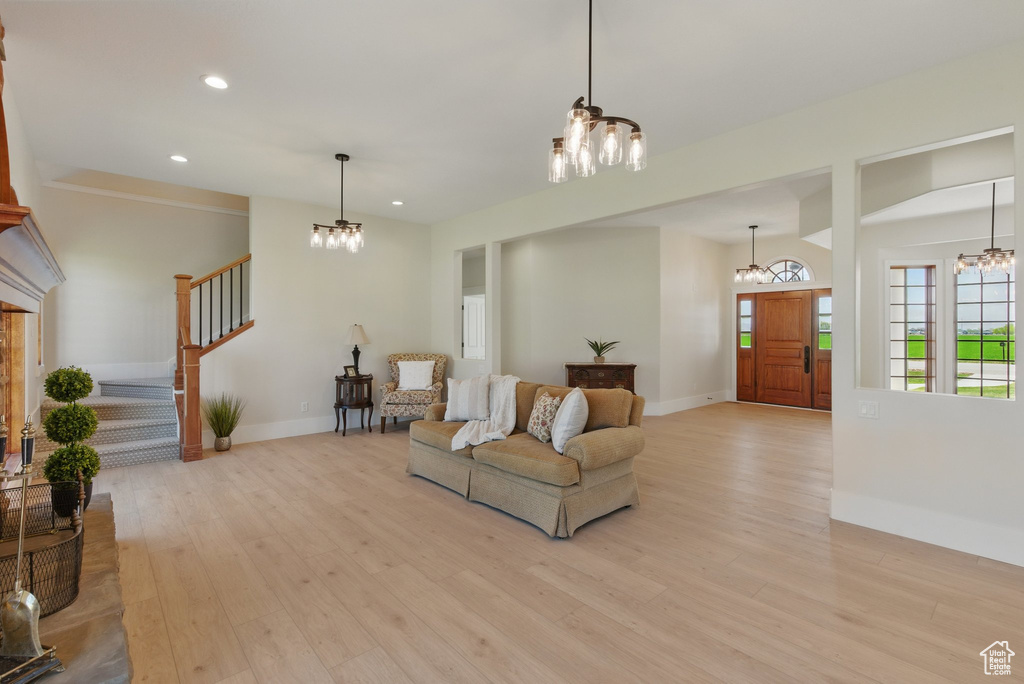 Living room featuring baseboards, stairs, a notable chandelier, and light wood finished floors