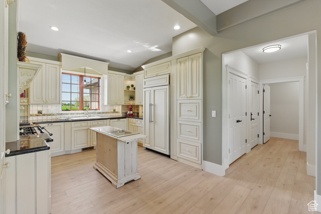 Kitchen with a center island, light wood-style floors, open shelves, paneled fridge, and tasteful backsplash