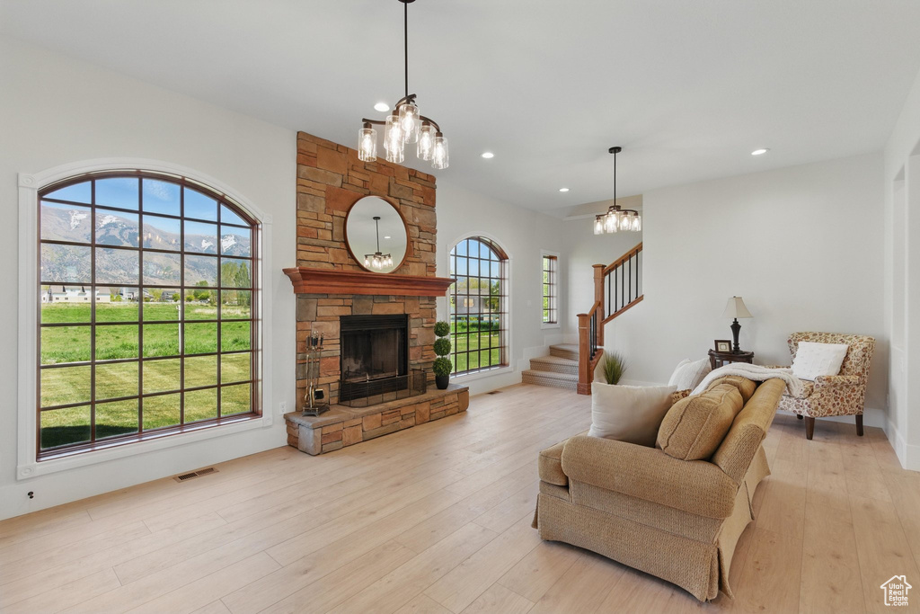 Living area with stairs, light wood-style floors, an inviting chandelier, and visible vents