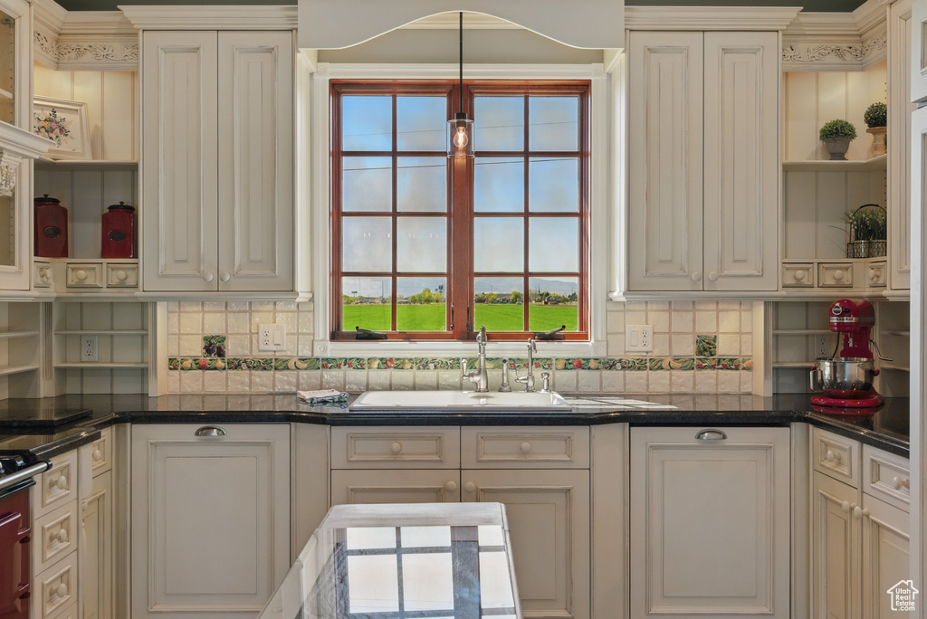 Kitchen with a sink, open shelves, decorative backsplash, and dark countertops