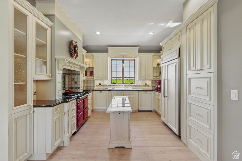 Kitchen with tasteful backsplash, cream cabinets, recessed lighting, light wood finished floors, and dark countertops