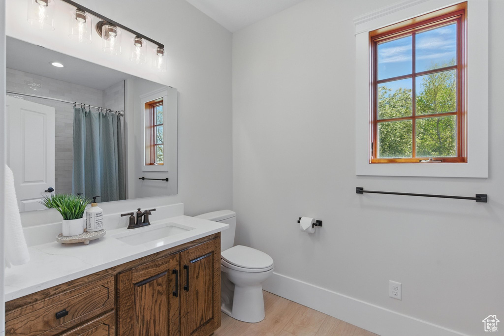 Bathroom with toilet, wood finished floors, vanity, a shower with shower curtain, and baseboards