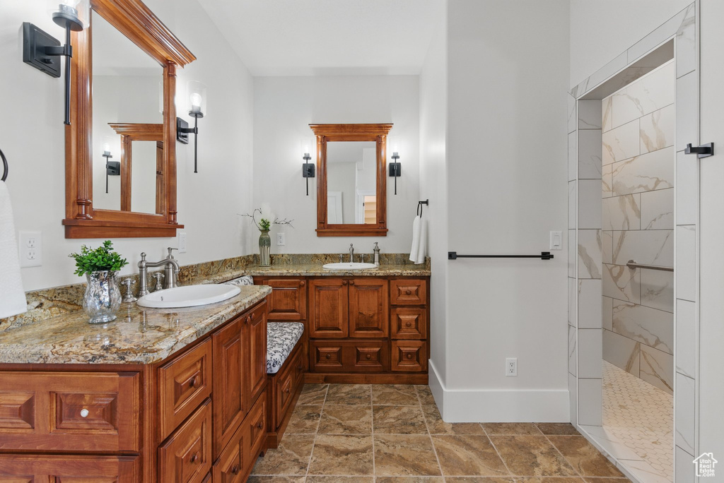 Bathroom featuring vanity, a walk in shower, and baseboards
