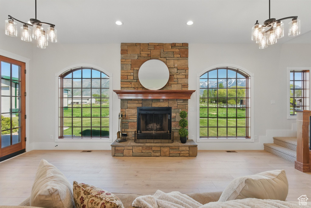 Unfurnished living room featuring a wealth of natural light, wood finished floors, and a notable chandelier