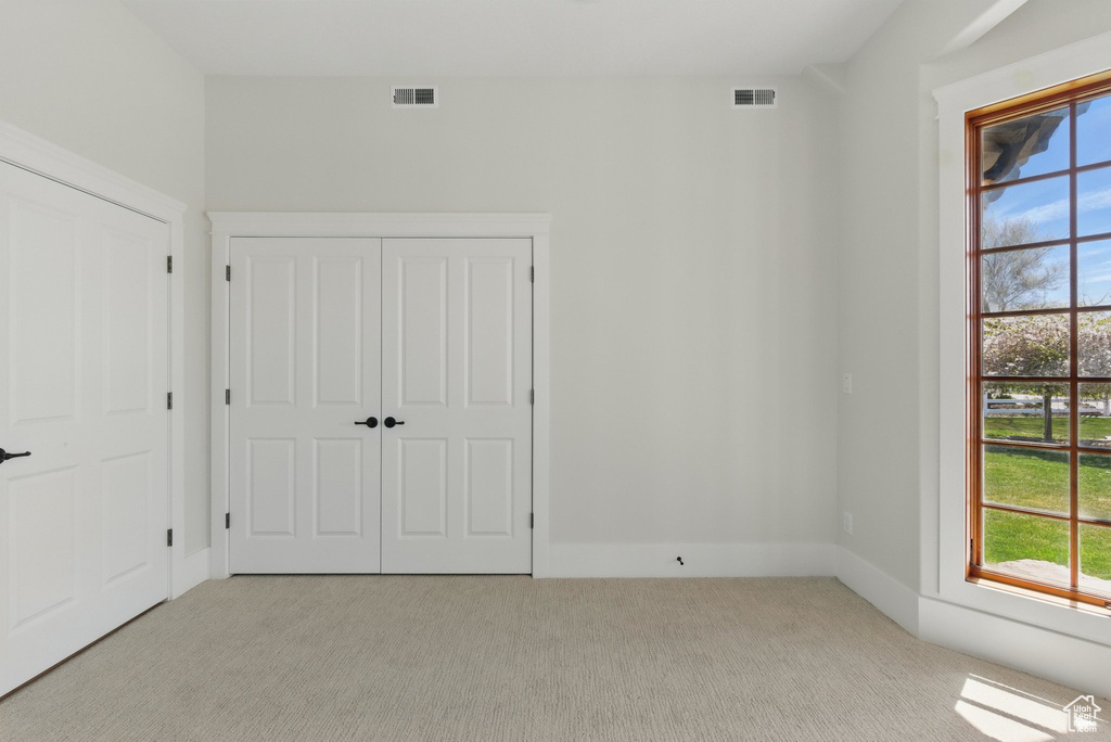 Unfurnished bedroom with light colored carpet, a closet, and visible vents