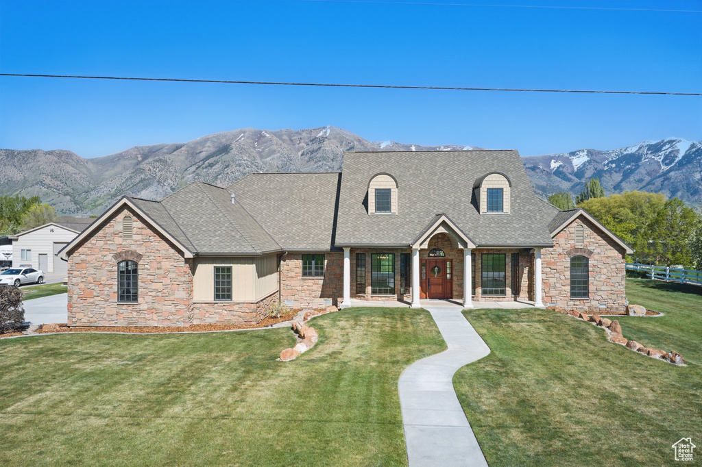 View of front of home with stone siding, a mountain view, and a front yard