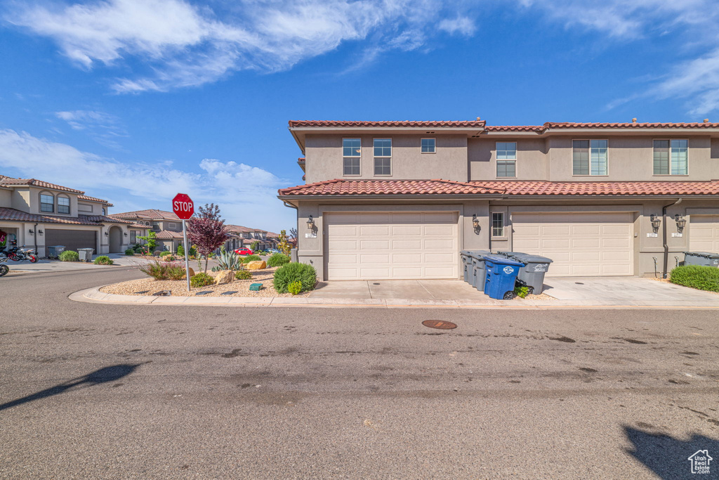 Mediterranean / spanish house with stucco siding, a tiled roof, a residential view, a garage, and concrete driveway