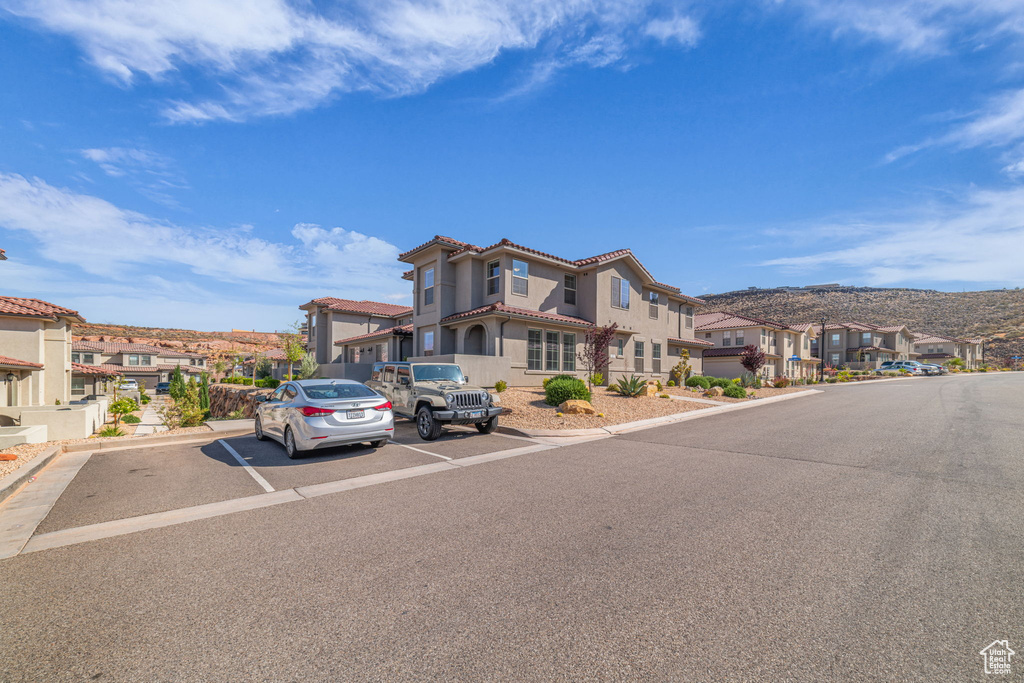 View of front of house featuring a residential view, a tiled roof, uncovered parking, and stucco siding