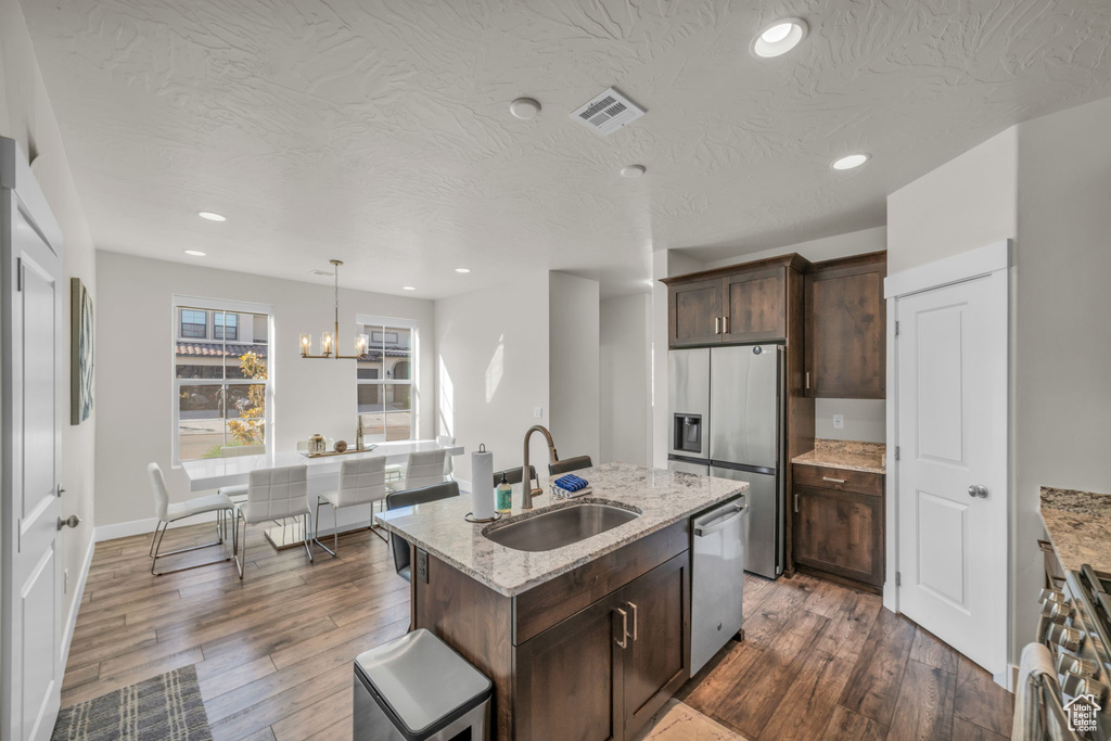 Kitchen featuring a sink, stainless steel appliances, dark wood finished floors, dark brown cabinets, and recessed lighting