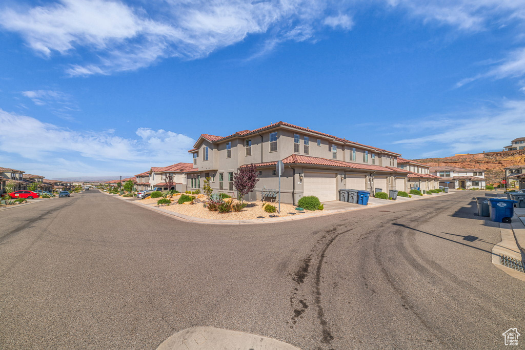 View of asphalt street featuring a residential view and curbs