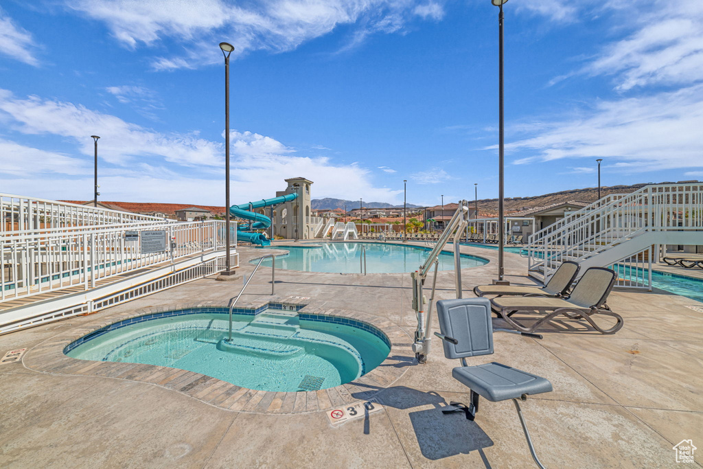 Community pool with a community hot tub, a patio, and a water slide