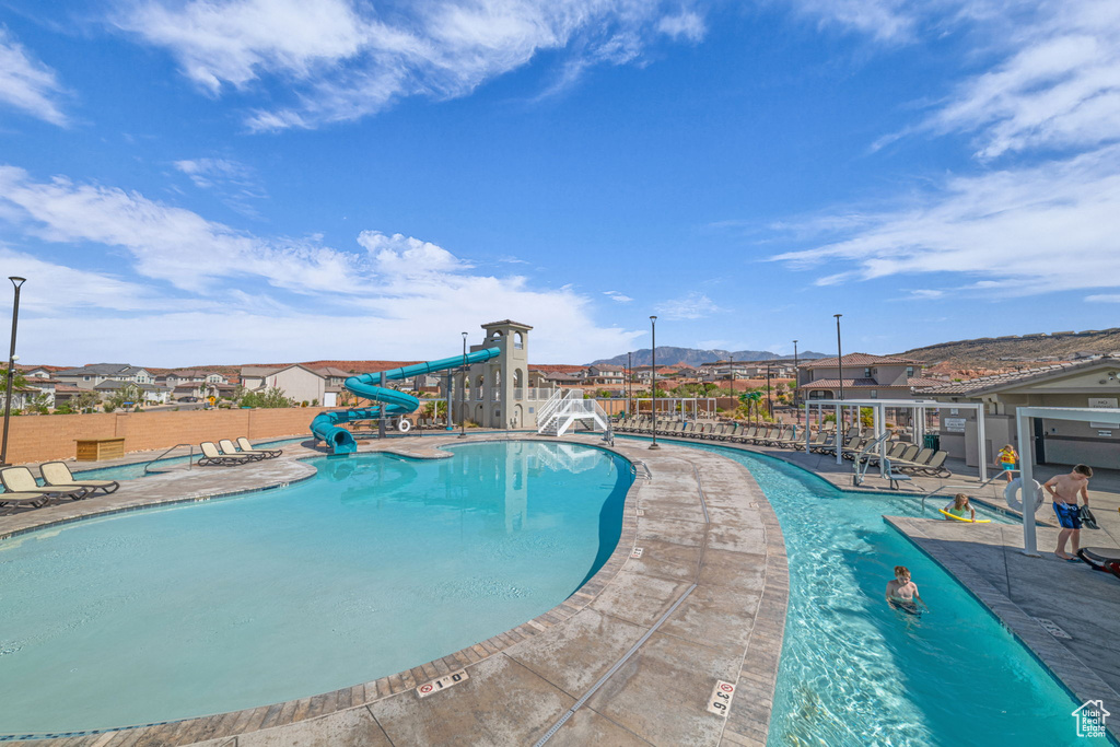 Community pool with a water slide, a patio area, and a mountain view