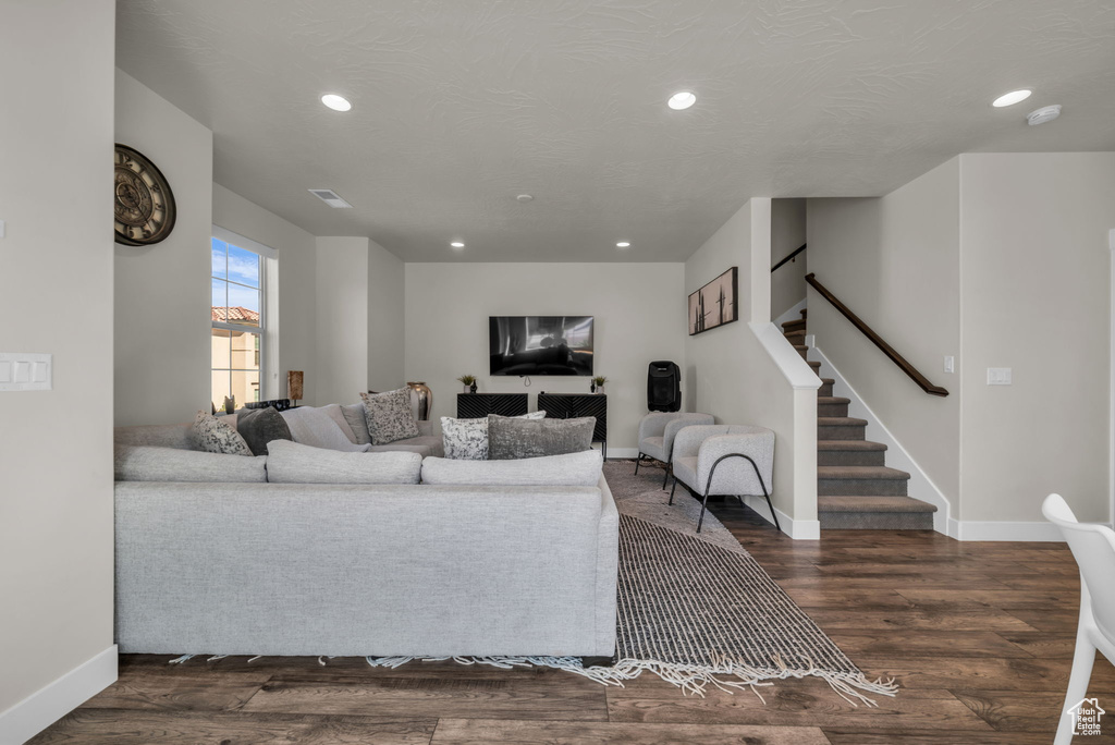 Living area featuring recessed lighting, baseboards, dark wood-style floors, and stairs