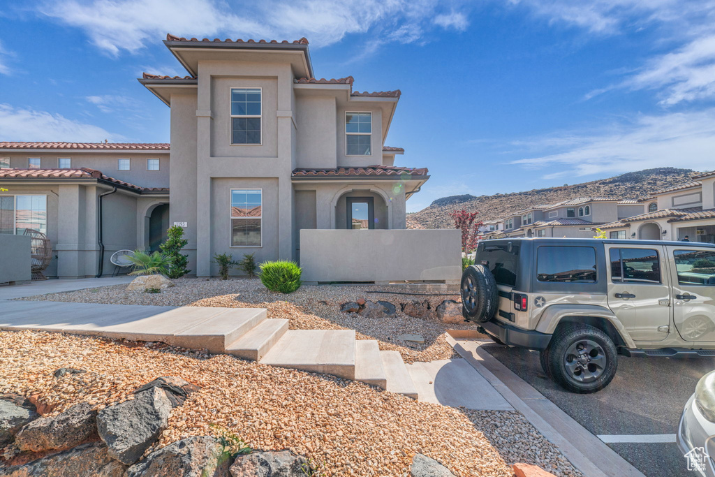 View of front of house featuring a tiled roof, stucco siding, and a mountain view