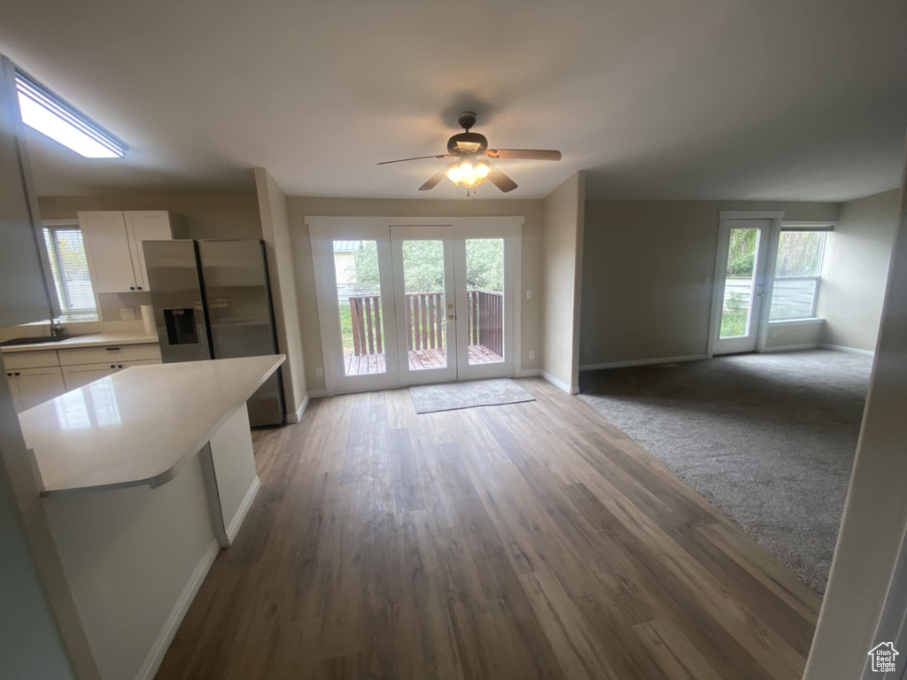 Unfurnished living room featuring baseboards, ceiling fan, light wood-style flooring, and a sink
