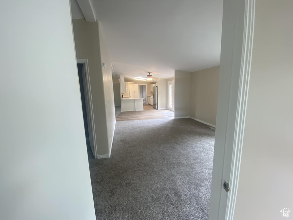 Carpeted spare room featuring baseboards and a ceiling fan