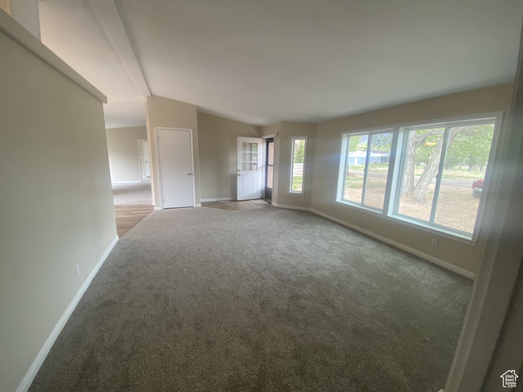 Unfurnished room with carpet, baseboards, and vaulted ceiling