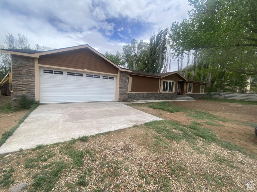 View of front of home featuring concrete driveway, stone siding, and an attached garage