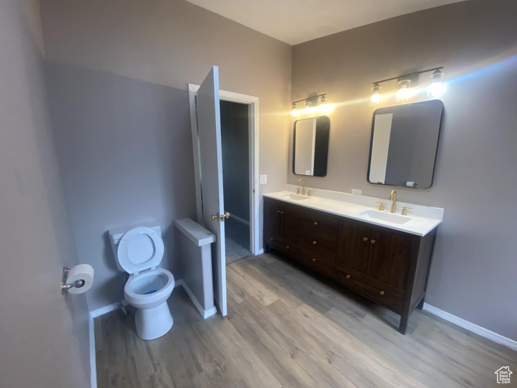 Full bath with wood finished floors, double vanity, and baseboards