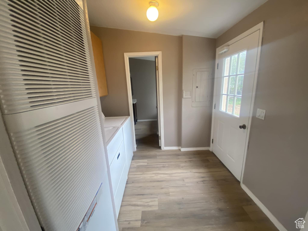 Laundry room with a heating unit, washer and clothes dryer, baseboards, and light wood-type flooring