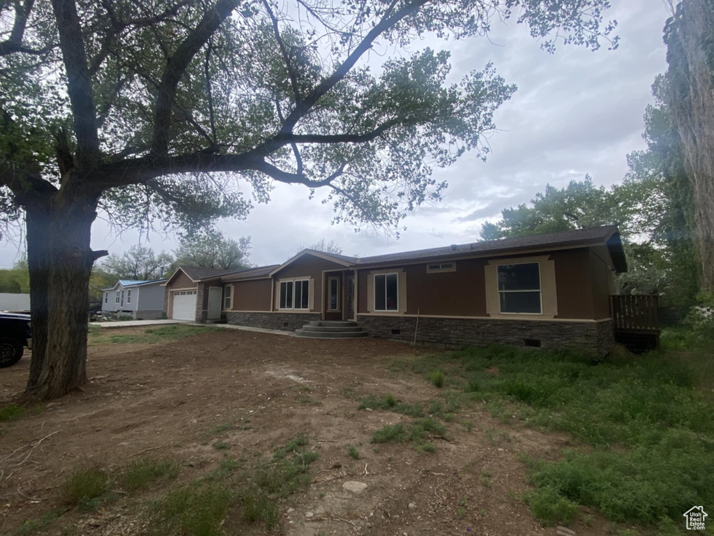 Single story home featuring an attached garage, stone siding, and driveway